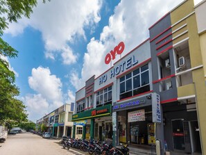 Un hotel con un cartel que dice 'OYO HOTEL' y una tienda '99 SPEEDMART' al otro lado de la calle.