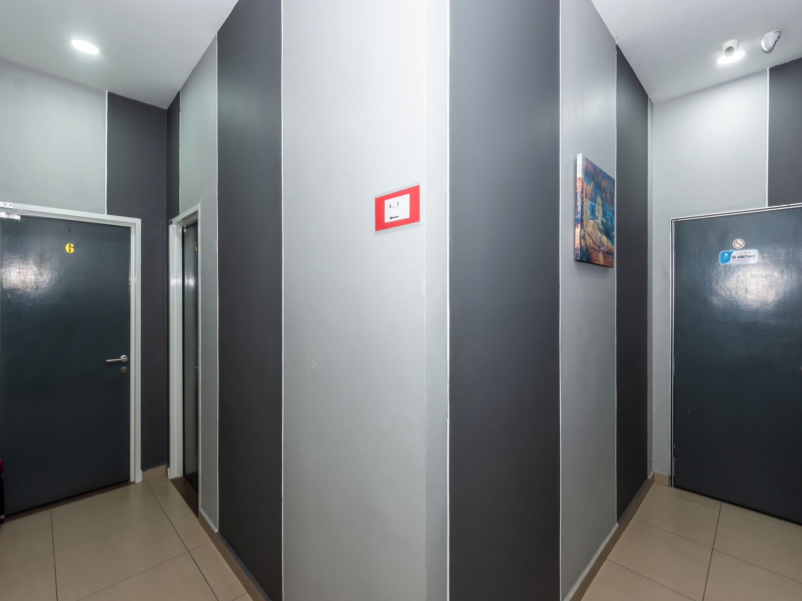 A corridor with doors, a red sign, and a painting on the wall.