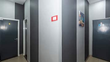 A corridor with doors, a red sign, and a painting on the wall.