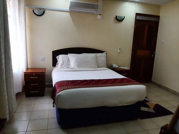 A bedroom with a bed, bedside tables, a telephone, and a door.