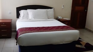 Une chambre bien rangée, avec un lit, une table de chevet et un appareil de climatisation fixé au mur.