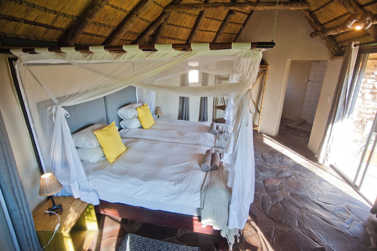 A bed with a canopy, a bedside lamp, and a stone floor.