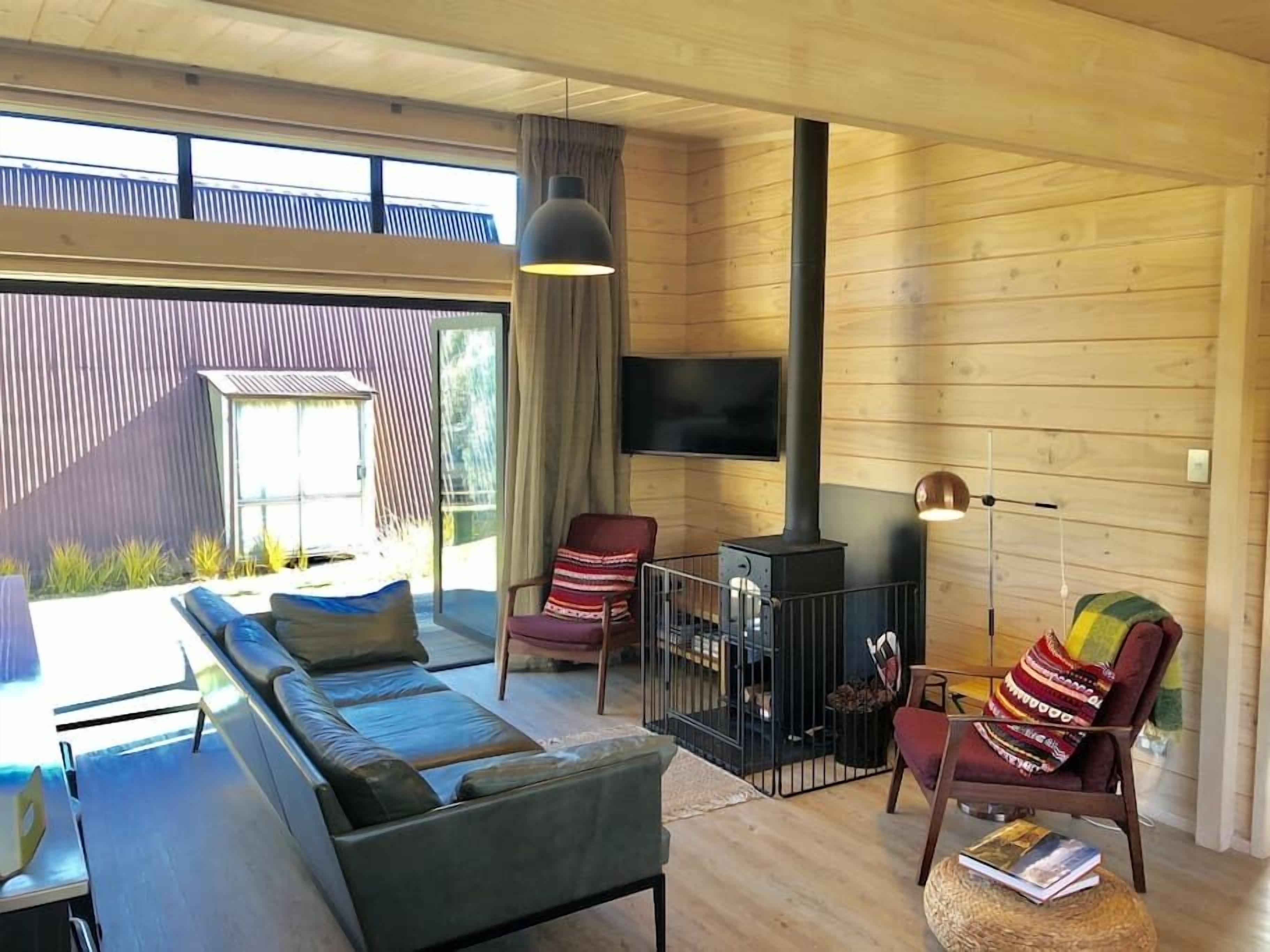 A modern interior with a sofa, chairs, a fireplace, and a television.