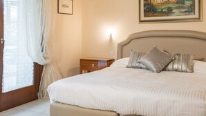 A neatly made bed with pillows, a bedside table, and a nightstand. - Miramonti Room & Breakfast (Iseo)