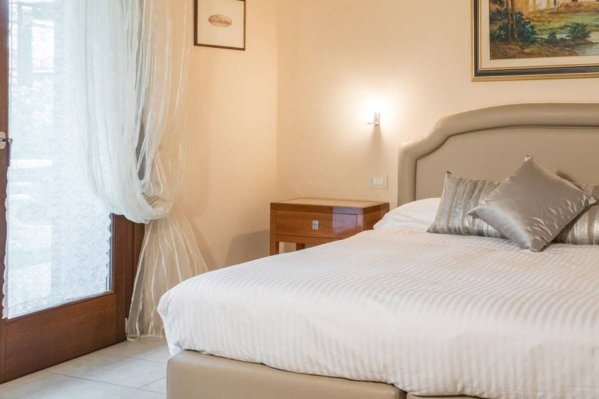 A neatly made bed with pillows, a bedside table, and a nightstand.