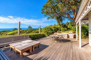 A wooden deck with a table and chairs, a bench, and a barbecue area. - Crescent Villa - Palm Beach Views & Hot Tub (Palm Beach)