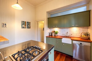 A kitchen with a gas stove, green cabinets, a dishwasher, and a wooden countertop. - Crescent Villa - Palm Beach Views & Hot Tub (Palm Beach)