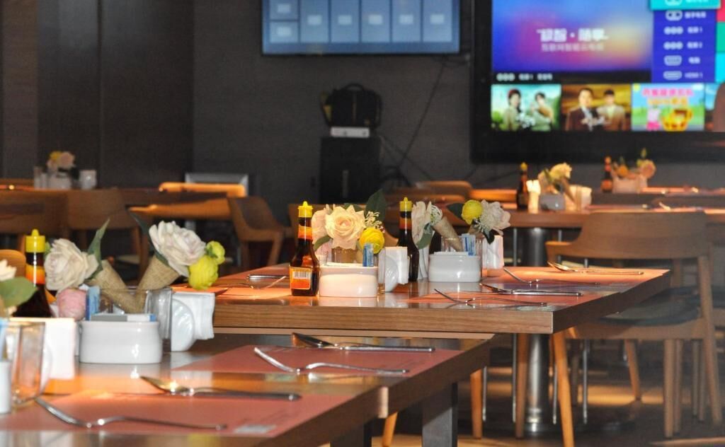 Un restaurante con mesas dispuestas para comer, equipadas con cubiertos, salsas y centros de mesa florales.