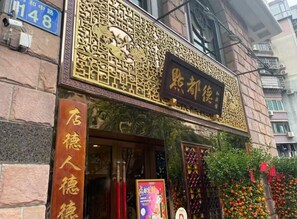 A hotel entrance with traditional Chinese architectural elements, a signboard, and a fruit display outside. - Grand Palace Hotel (Guangzhou)