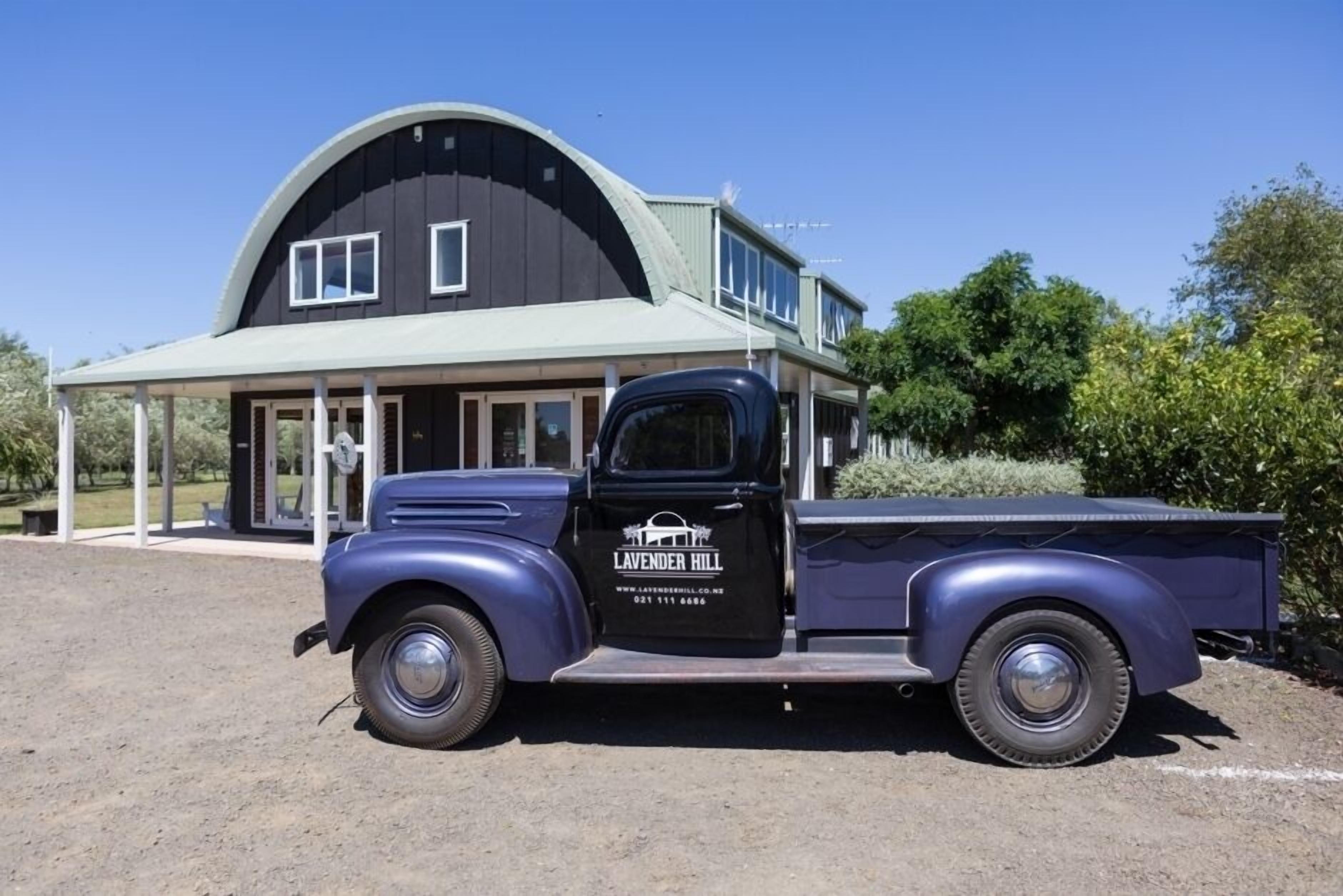 A vintage blue truck parked in front of a modern house with a large garage.
