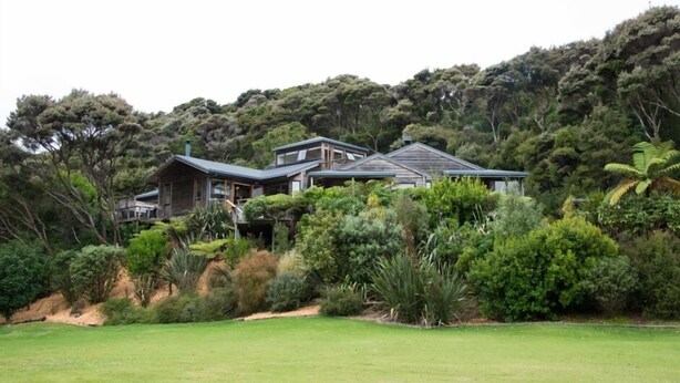 A large house surrounded by dense greenery and hills.