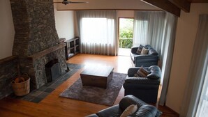 A living room with a stone fireplace, a sofa set, and a view of the outdoors.