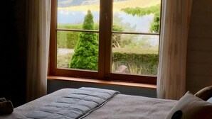 A bedroom with a large window offering a view of a lake and greenery. - Maison du Campagne in French Farm, Akaroa (Wainui (Banks Peninsula))