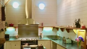 A kitchen with a stove, oven, and sink, with wooden shelves above the counter. - Maison du Campagne in French Farm, Akaroa (Wainui (Banks Peninsula))