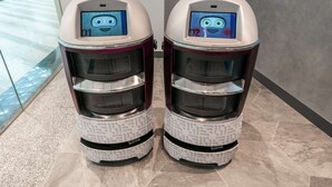 Two self-service kiosks with digital displays, positioned on a tiled floor in a commercial setting.