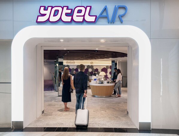 Der Eingang eines Hotels namens 'yotel AIR' mit einer Rezeption, einer Theke und einem modernen Innenraumdesign.
