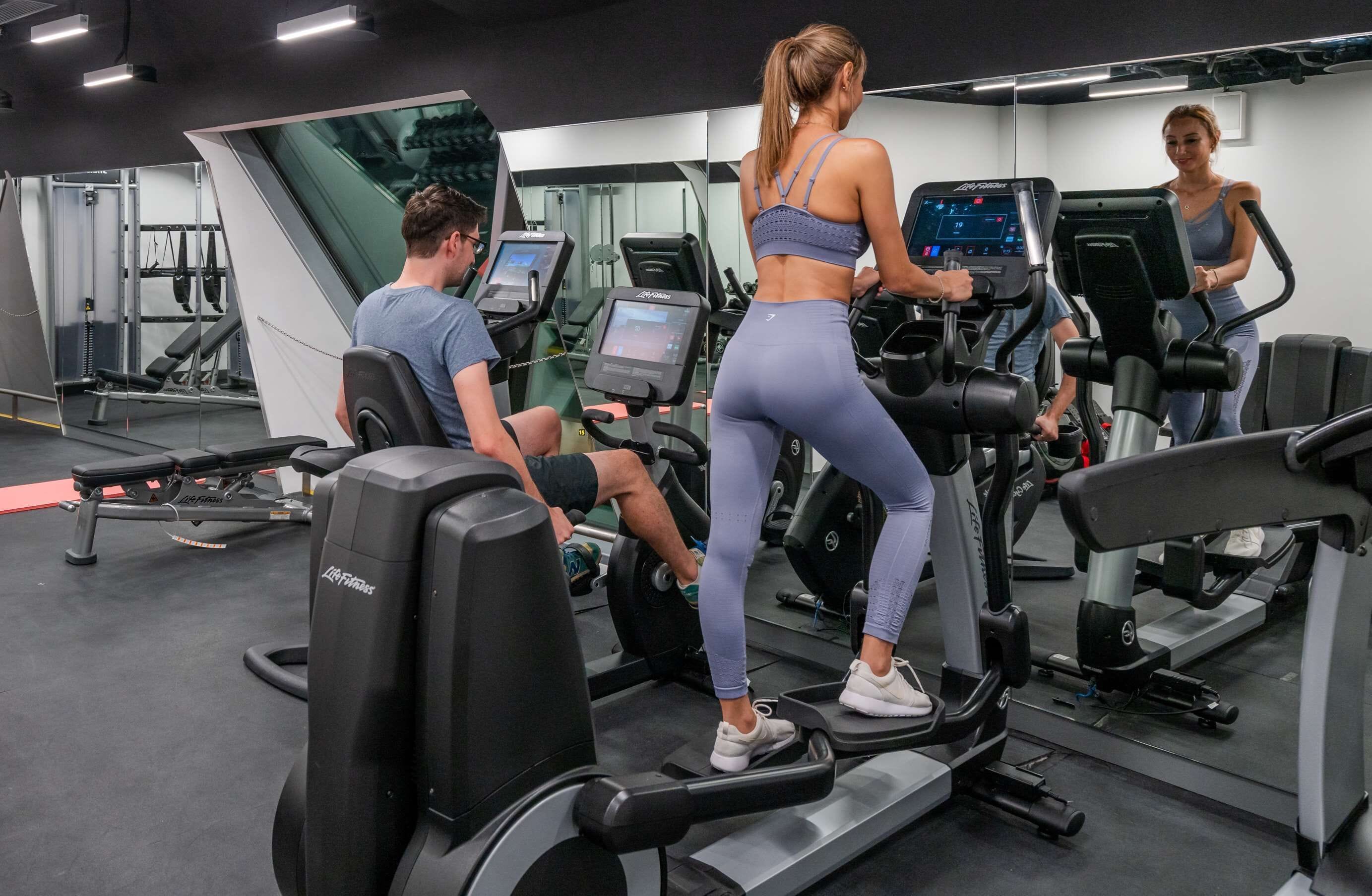 A gym with treadmills, weight machines, and a mirrored wall.