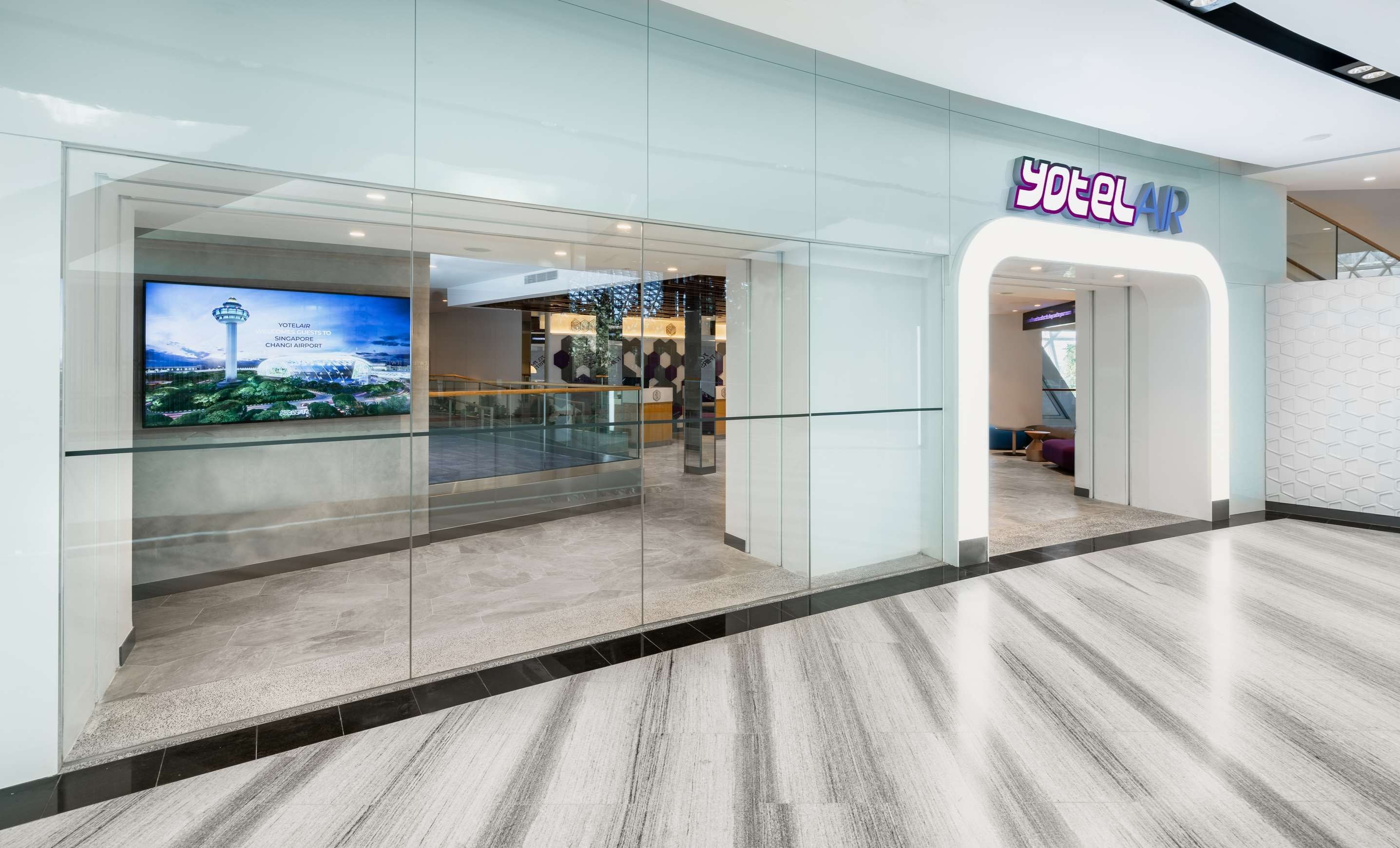 A hotel entrance with a modern design, a digital display, and a sign for 'Yotelair'.
