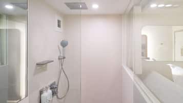 A modern bathroom with a glass shower enclosure, a handheld showerhead, and a wall-mounted soap dispenser.