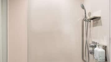 Un espace douche moderne doté d’un pommeau de douche à main, d’un robinet mural et d’un panneau de commande.