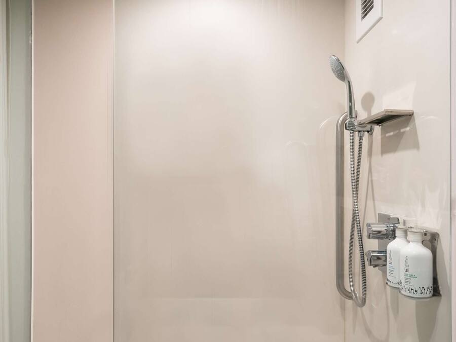 Un espace douche moderne doté d’un pommeau de douche à main, d’un robinet mural et d’un panneau de commande.