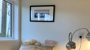 Un petit bureau en bois orné d’un motif floral, un banc assorti, un tableau encadré accroché au mur et une lampe sur pied.