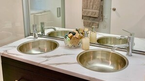 Une salle de bain avec deux lavabos, un grand miroir et une douche à parois de verre.
