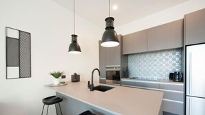 A modern kitchen with a central island, bar stools, pendant lighting, and stainless steel appliances.