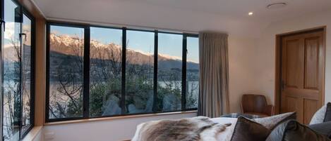 A bedroom with a large window offering a mountain view.