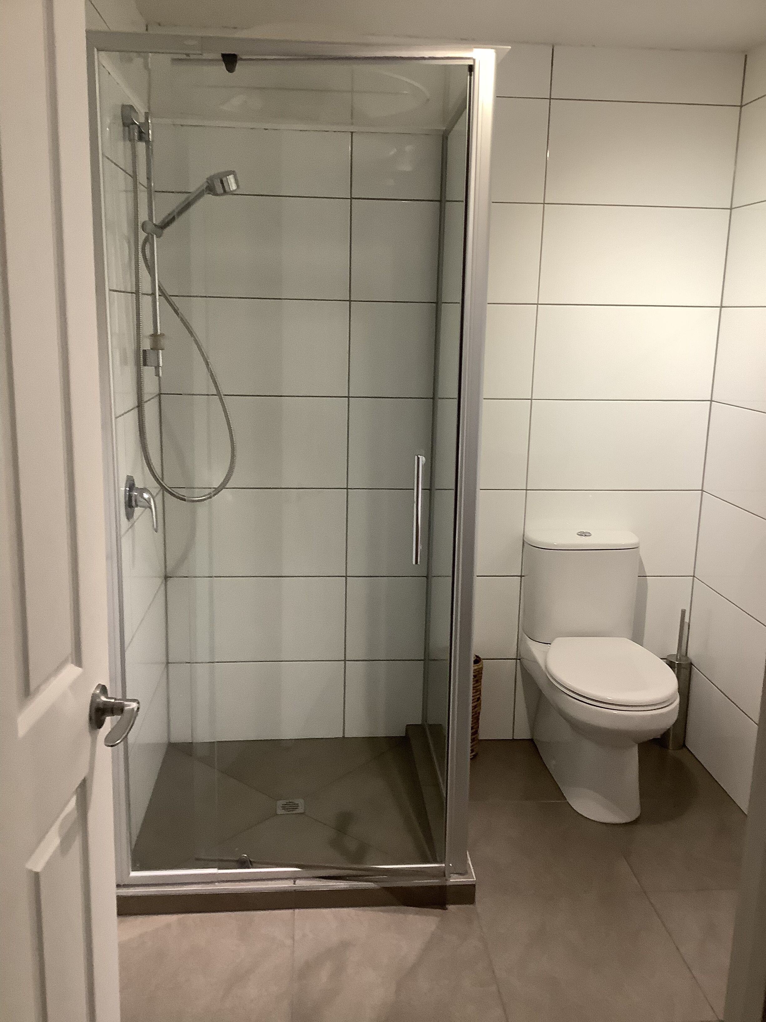 Un bagno con doccia vetrata, un water e una porta.
