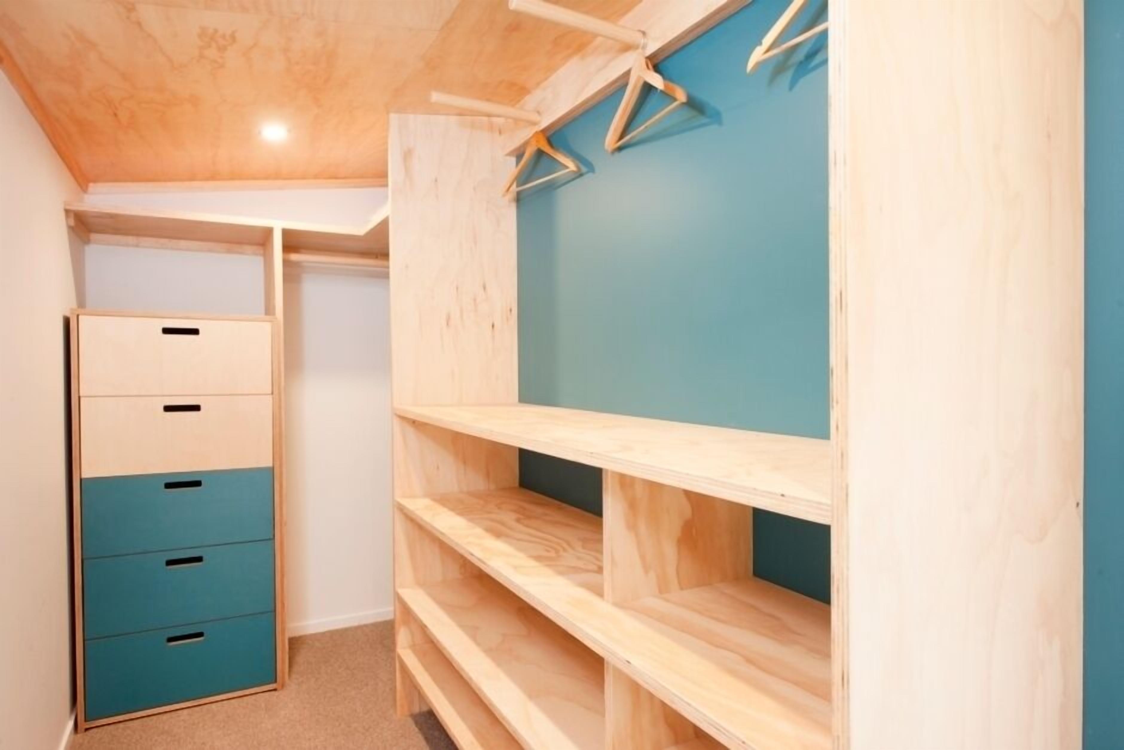Een houten kast met meerdere lades en planken, een blauwe wand en een houten plafond.