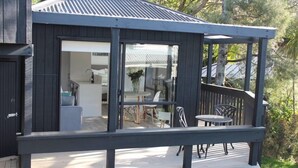 A modern house with a covered porch, a dining area with outdoor furniture, and a visible kitchen area.