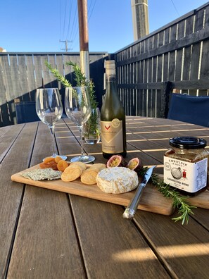 Ein Holztisch mit einer Weinflasche, Gläsern, Käse, Crackern und einem Glas karamellisierter Zwiebelaufstrich.