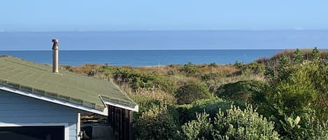 A coastal property with a covered porch, a chimney, and a view of the ocean.