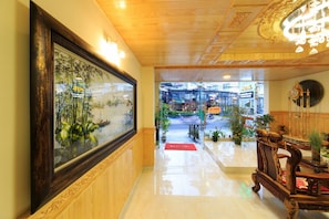 Un hall d’hôtel avec un grand tableau encadré, un comptoir d’accueil et une vue sur l’entrée de l’hôtel.