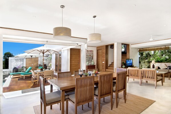 Un comedor amplio con una mesa y sillas de madera, un televisor y vistas al exterior.