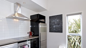 A modern kitchen with stainless steel appliances, a black backsplash, and a window with a view of plants.