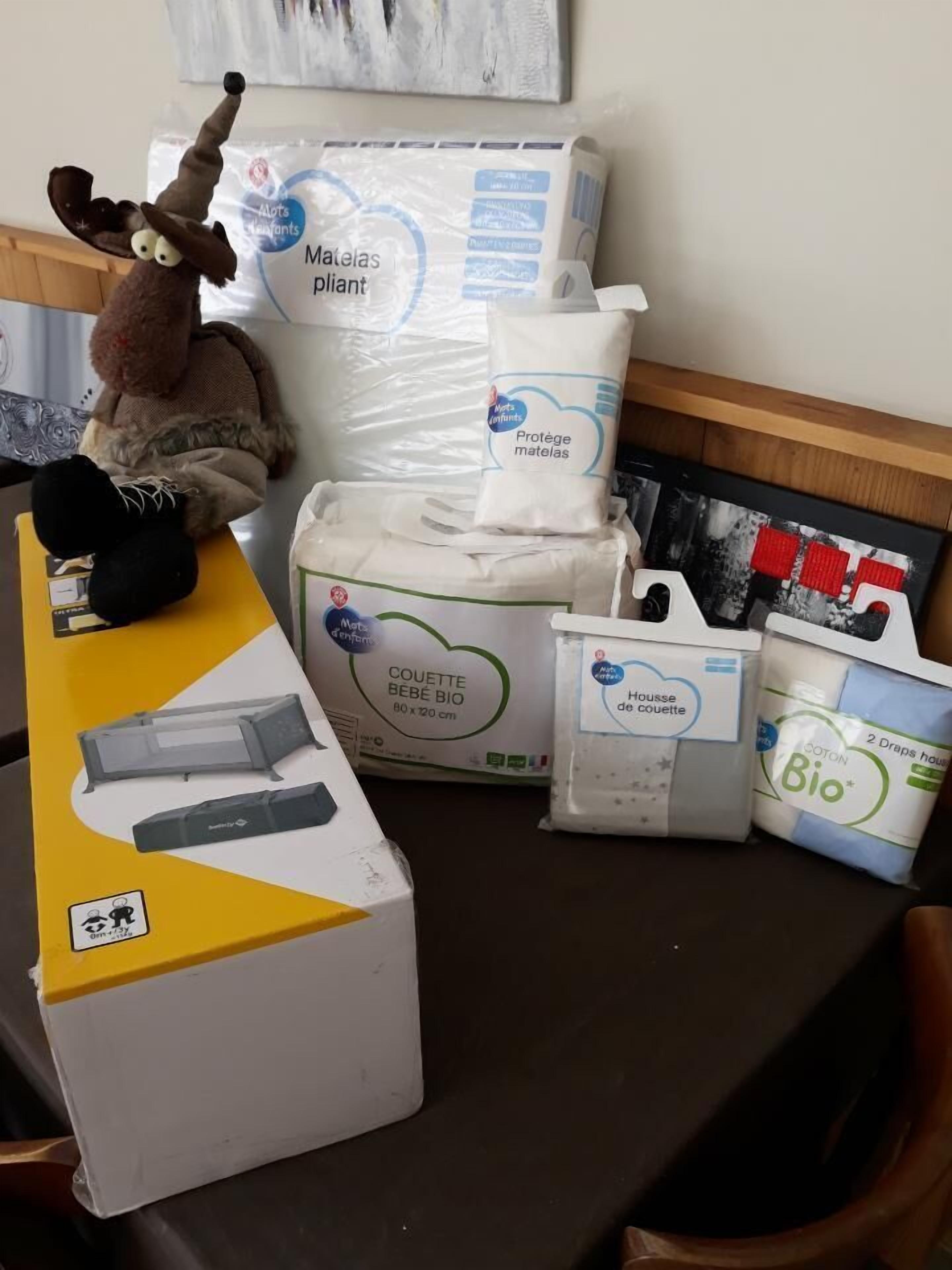 Mostrador de recepción de hotel con un peluche, un cambiador para bebés y varios servicios, incluyendo un biberón y un paquete de hisopos de algodón.