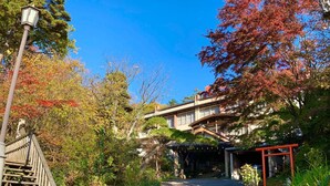 A traditional Japanese-style building with a wooden entrance gate, a stone pathway leading to the entrance, and a street lamp on the left. - Kirishimaya Ryokan (Kusatsu)