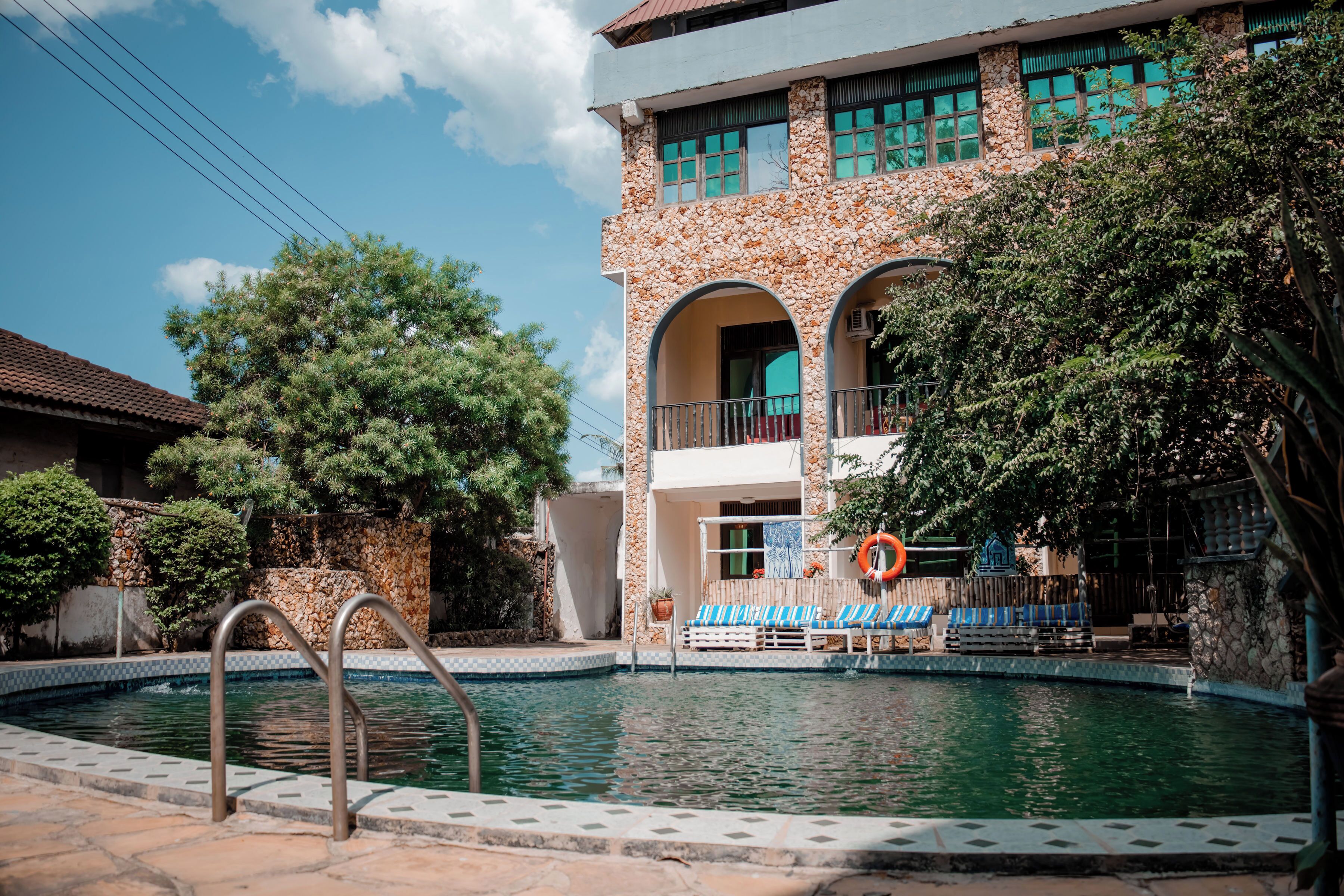 Una piscina al aire libre, sombrillas, sillones reclinables de piscina
