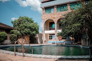 Una piscina al aire libre, sombrillas, sillones reclinables de piscina