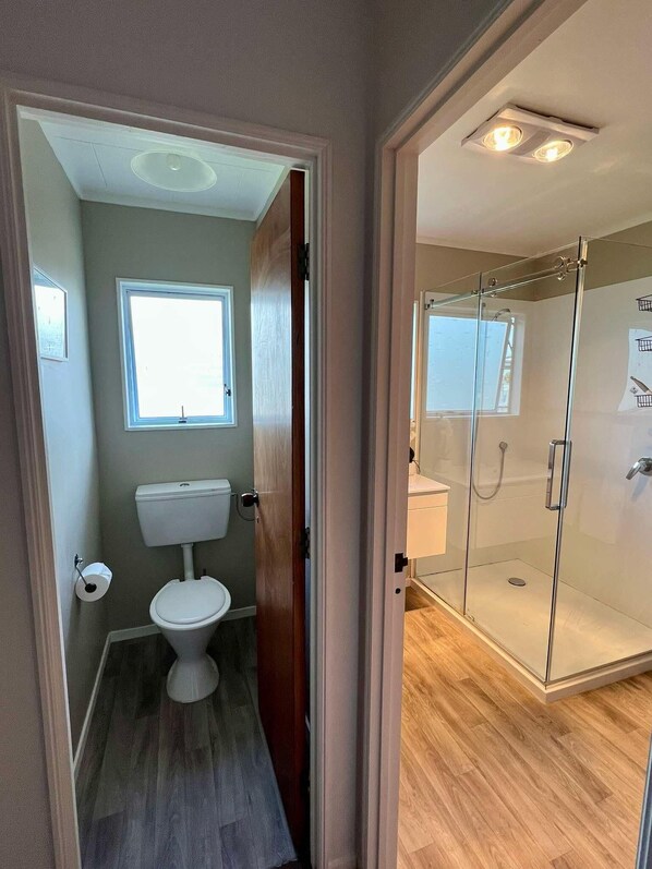 Un baño con inodoro, ventana y cabina de ducha de vidrio.