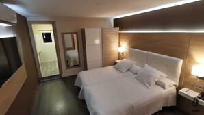 A modern hotel room with a large bed, bedside tables, a TV, and a mirror. - Rose des Pyrénées (Belvianes-et-Cavirac)