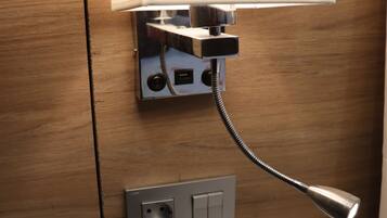 A hotel room with a desk, a telephone, a lamp, and a power outlet.