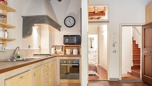 A compact kitchen with wooden cabinets, a microwave, a sink, and a clock on the wall. - San Lorenzo Apartment (Florence)