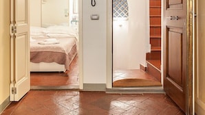 A room with a bed, a wooden ceiling, a door, and a staircase. - San Lorenzo Apartment (Florence)