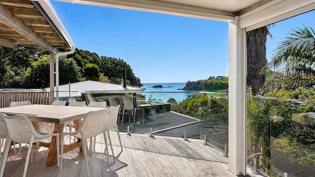 A wooden deck with a table and chairs, overlooking a coastal landscape with clear skies. - Island View - Walk to Palm Beach (Palm Beach)