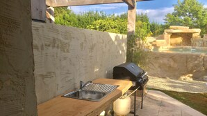 Cocina exterior con pileta, parrilla y dispensador de agua.