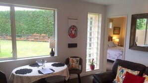 Una habitación con una mesa de comedor, un sofá de cuero negro y una cama al fondo.