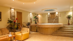 A spa area with a hot tub, a sofa, and a staircase leading to an upper level. - Hotel Galaktika (Lviv)